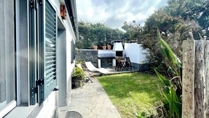 Une terrasse avec un barbecue, des sièges d’extérieur et un chemin de pierre menant à la maison.