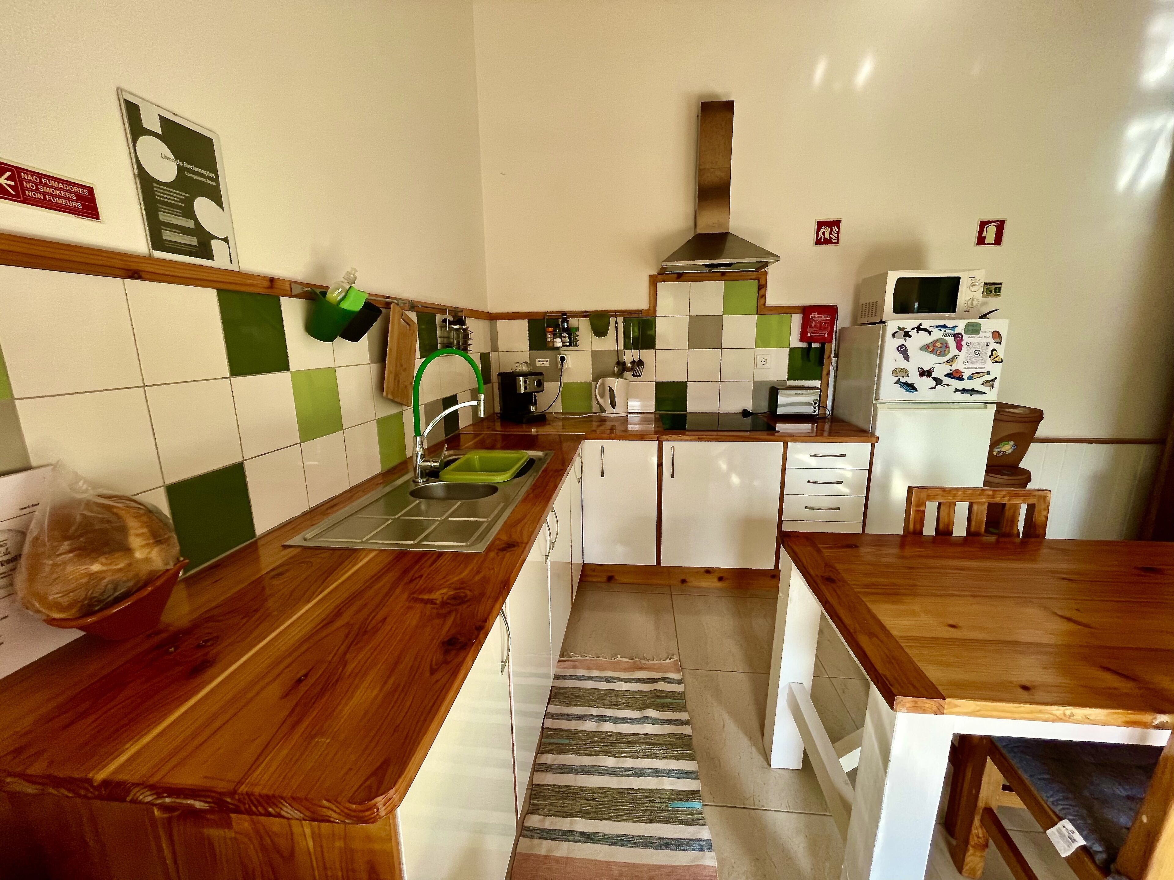 A kitchen with a wooden countertop, a sink, a stove, and a refrigerator.