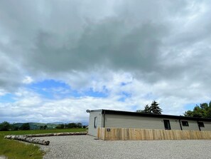 A single-story building with a gravel driveway and a wooden fence.