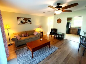 Relax in this inviting living room with a sofa, coffee table, and dining area leading to a kitchen.