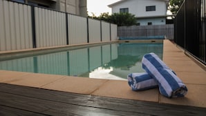 A swimming pool with a wooden deck, a towel, and a fence. - Weipa Motel Resort (Rocky Point)