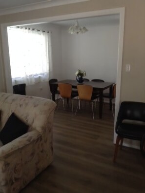 A dining area with a table and chairs, a sofa, and a hanging light fixture. - WITHAVEN- Perfect to Jervis Bay Beaches and Shops  (Old Erowal Bay)