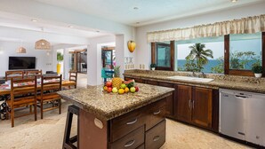 Una cocina con encimeras de granito, armarios de madera y un cuenco de frutas.
