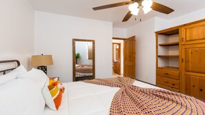A hotel room with a bed, a nightstand, a lamp, a wardrobe, and a ceiling fan.