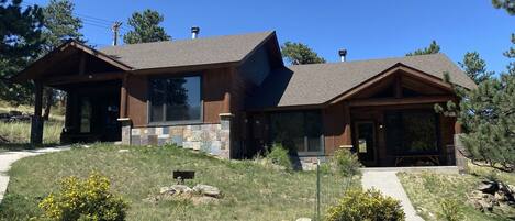 A two-story house with a stone foundation and a sloped roof.