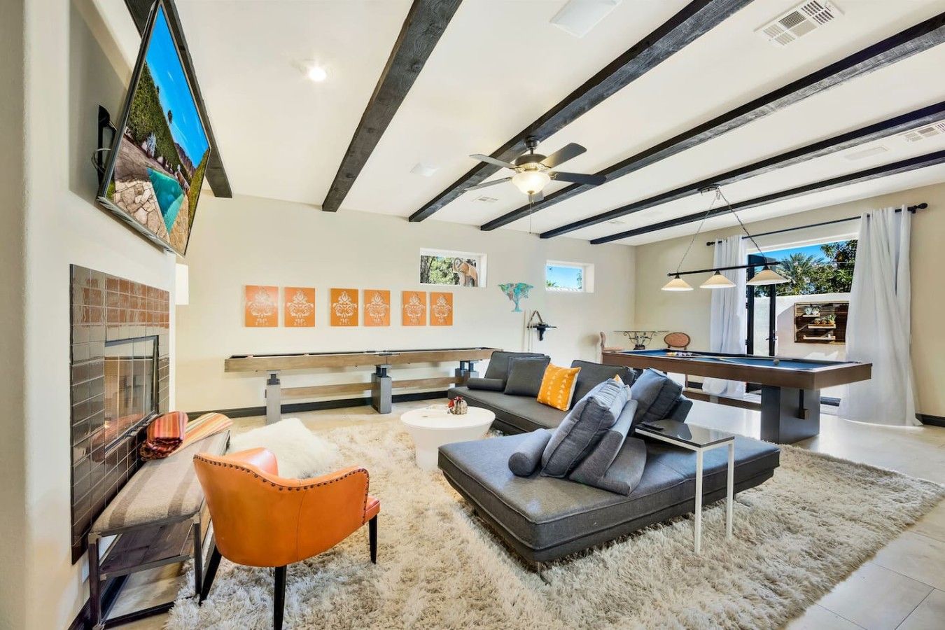 A modern living room with a fireplace, sofa, and pool table.