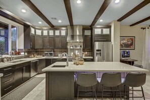 Una cocina moderna con armarios oscuros, electrodomésticos de acero inoxidable y una isla grande con taburetes de bar.
