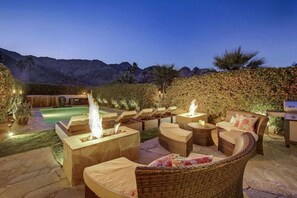 An outdoor patio with lounge chairs, a fire pit, and a swimming pool.