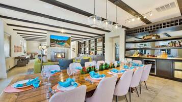 A dining area with a long wooden table set for a meal, surrounded by chairs.