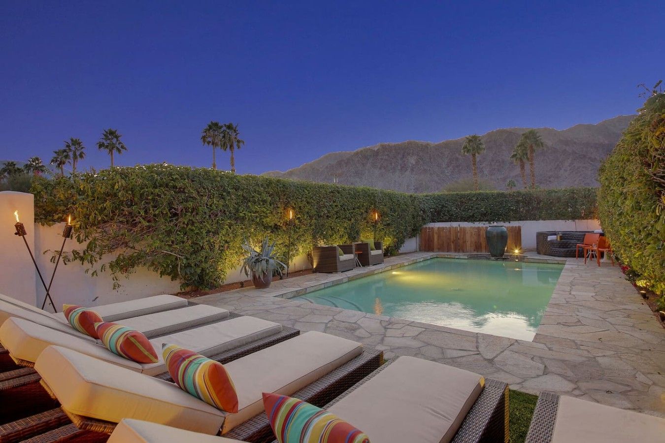 A poolside area with lounge chairs, a hot tub, and a waterfall feature.