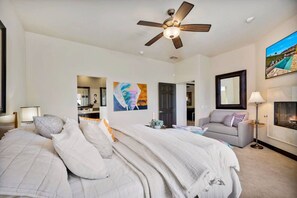 A bedroom with a bed, a ceiling fan, a sofa, a lamp, and a painting on the wall.