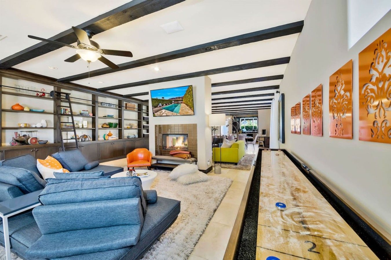 A modern living room with a fireplace, a billiard table, and a sofa.