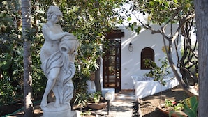Una statua in un giardino con un edificio bianco sullo sfondo.