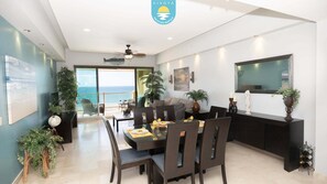 A modern dining area with a table set for four, a sofa, and a view of the ocean.