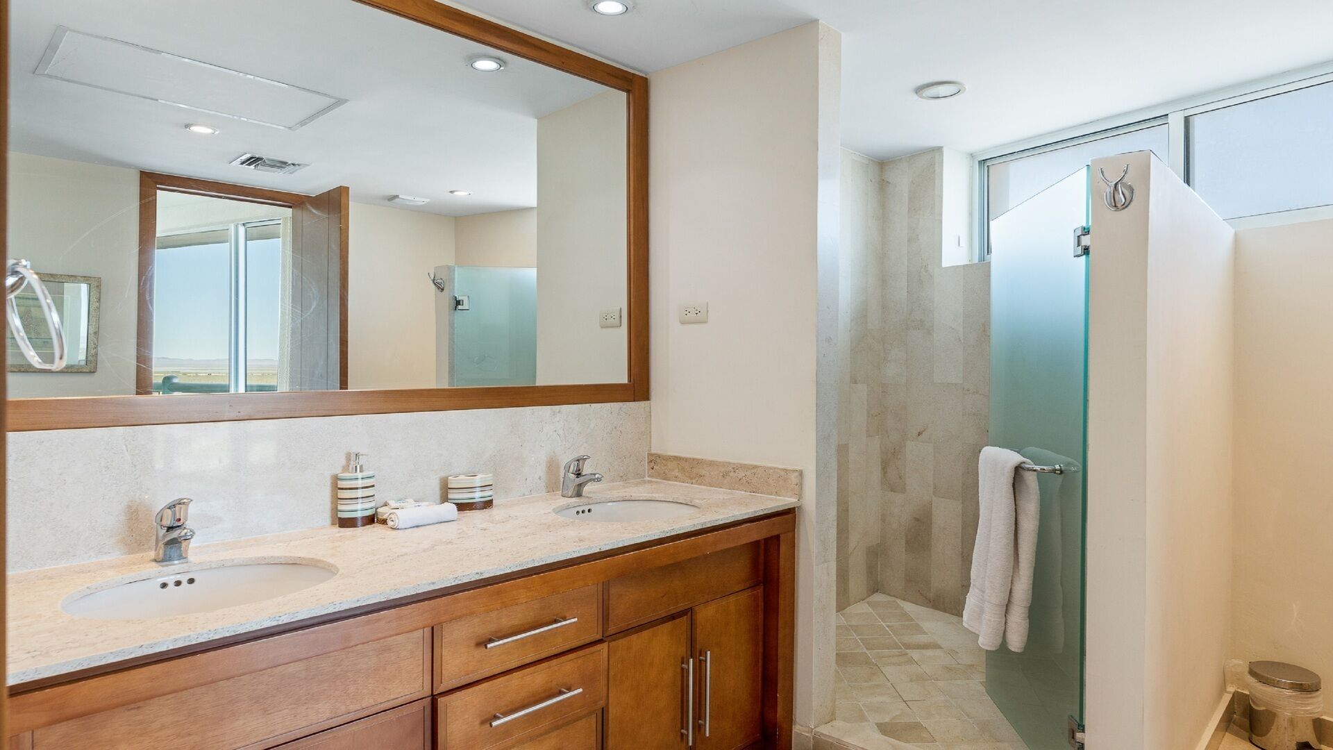 Un bagno con due lavandini, uno specchio grande, mobili in legno e zona doccia.