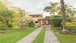 A pathway leading to a building with a brick structure and a tiled roof. - Beautiful house in Chapala with an incredible garden with pool (Chapala)