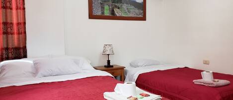 A hotel room with two beds, a painting of Machu Picchu, a nightstand with a lamp, and a cat bed.