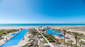 A resort with multiple swimming pools, a beach, and palm trees.