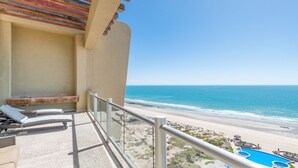 A balcony with a view of the beach and a pool.