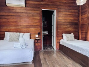 A room with two beds, wooden walls, a small table with a lamp, and a closet. - Hotelito Villas Holbox (Isla Holbox)