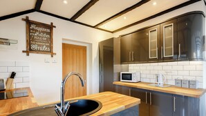 A modern kitchen with a wooden countertop, stainless steel appliances, and a sign on the wall. - Serenity Sands - UK30265 (Goodrington, near Paignton)