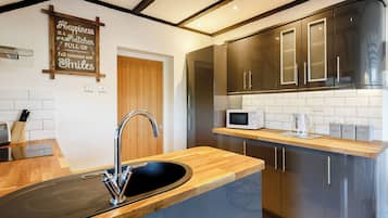 A modern kitchen with a wooden countertop, stainless steel appliances, and a sign on the wall.