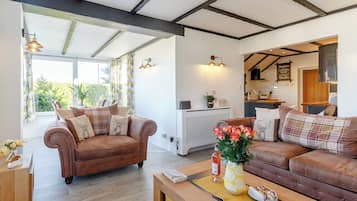A spacious living area with a brown leather sofa, a wooden coffee table, and a view into the kitchen.