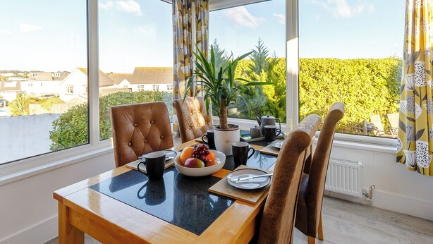 A dining area with a table, chairs, a potted plant, and a view of the outside. - Serenity Sands - UK30265 (Goodrington, near Paignton)