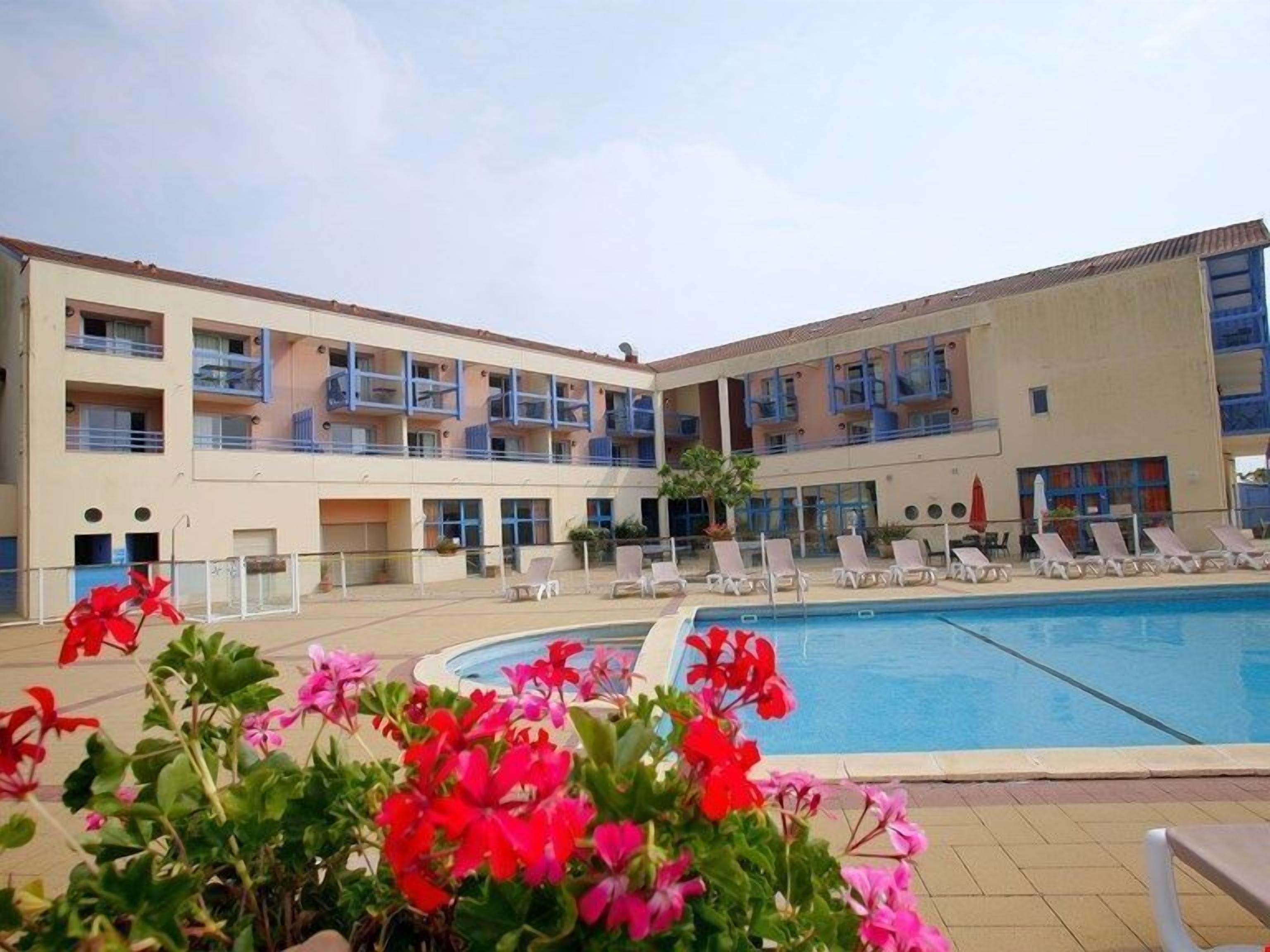 Un hôtel doté d’une piscine, de plusieurs balcons et de chaises longues.