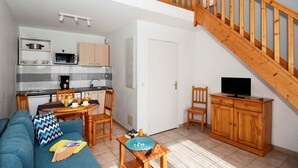 Ein kompakter Wohnbereich mit Küchenzeile, Essbereich, Sofa, TV-Stand und einer Treppe.