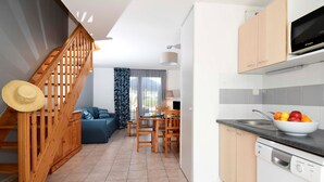 A modern kitchen with wooden cabinets, a built-in dishwasher, and a fruit bowl on the counter.