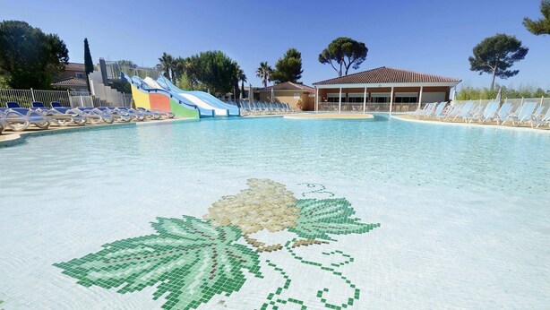 A swimming pool with a mosaic of leaves and a slide.
