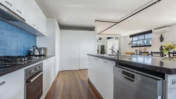 Une cuisine moderne avec des armoires blanches, un comptoir noir et des appareils électroménagers en acier inoxydable.