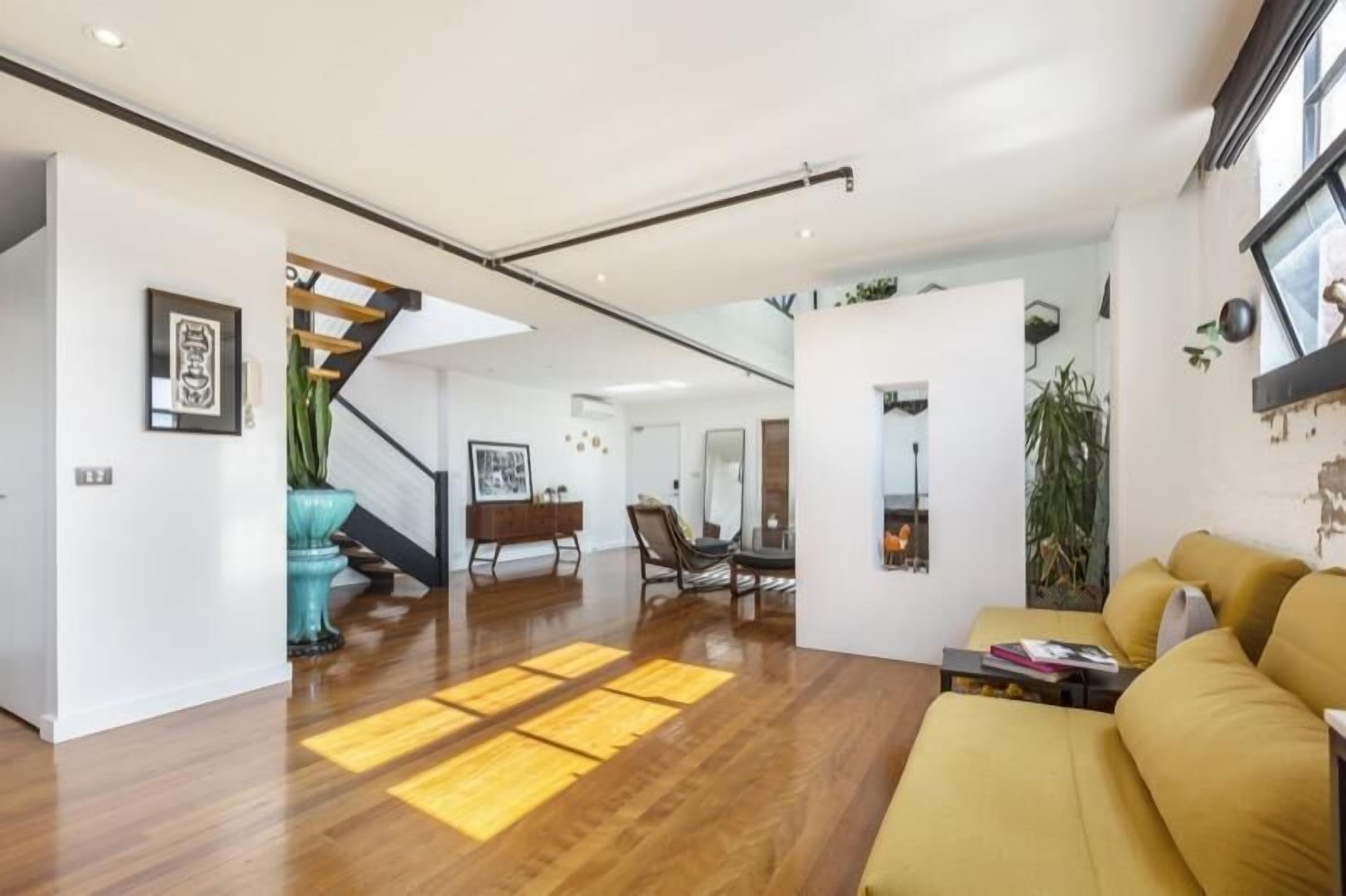 Un salon moderne avec un canapé, une table basse et un escalier menant à un autre niveau.