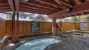 An outdoor hot tub area with wooden railings and a stone wall.