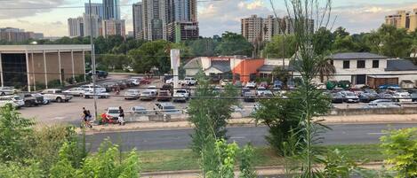 A parking lot with various cars, a building with a sign that reads "Cidercade," and a city skyline with tall buildings in the background.