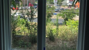 Vista attraverso una finestra su un panorama urbano, con grattacieli e un parcheggio.