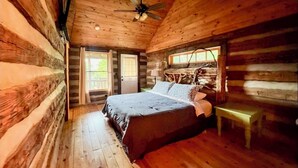 A log cabin bedroom with a wooden bed, a ceiling fan, and a bench. - Authentic Log Cabin on Dancy Mountain near McGrady, North Carolina (McGrady)