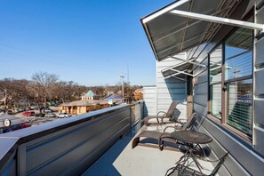 A balcony with two chairs and a table, overlooking a parking area and buildings in the background. - OLIVER 12 South (Nashville)
