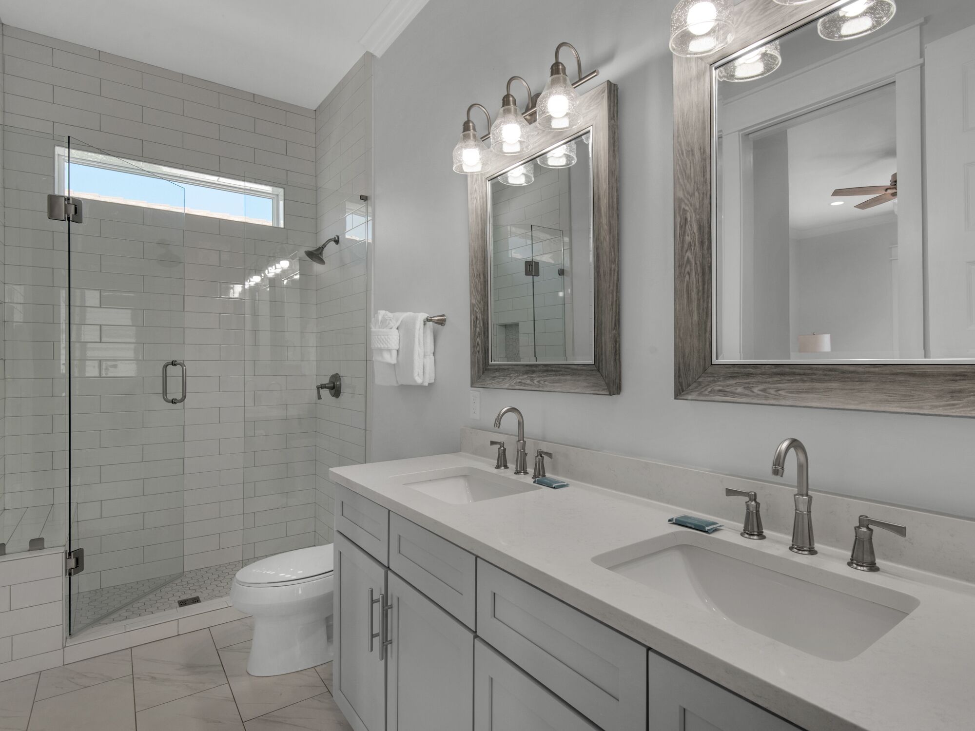 Une salle de bain moderne dotée d’une douche à l’italienne, de deux vasques et d’un grand miroir.