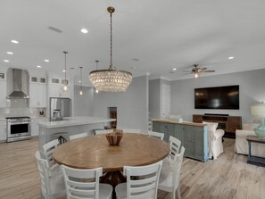 Enjoy meals around the central dining table, surrounded by comfortable seating and a stunning chandelier.