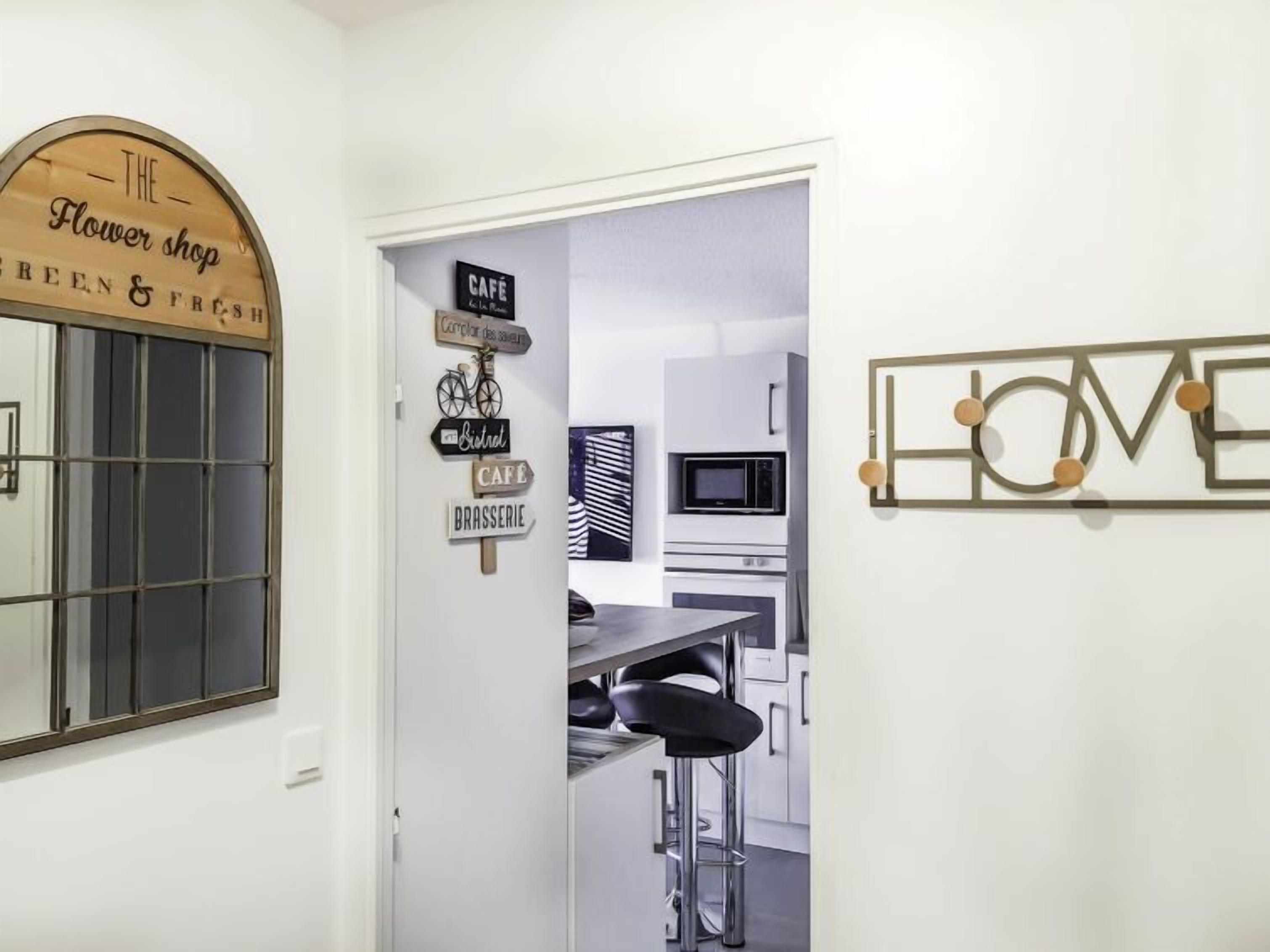 A modern kitchen with a bar area, a sign for 'The Flower Shop', and a 'LOVE' sign on the wall.