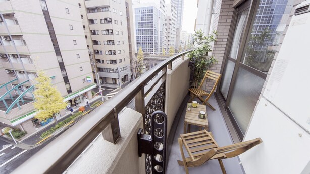 A balcony with a view of a cityscape, a small table with chairs, and a potted plant. - Nestle Tokyo Deluxe Akihabara 05 (Tokyo)