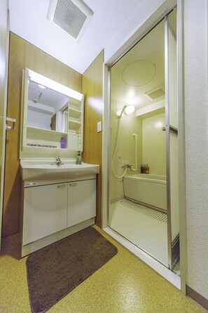 A bathroom with a sink, mirror, and shower.