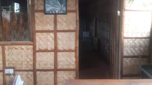 Fachada de madeira com parede de azulejos, porta de entrada e uma pequena mesa com um ventilador.