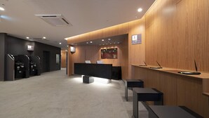 A modern reception area with a wooden reception desk, a black counter, and a seating area with tables. -  Washington R&B Hotel Sendai Higashiguchi (Sendai)