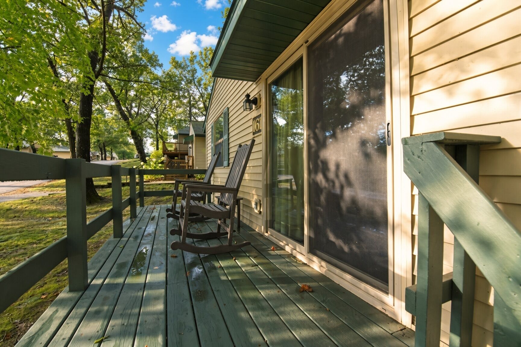 Une terrasse en bois avec des fauteuils à bascule, un porche couvert et une fenêtre grillagée.