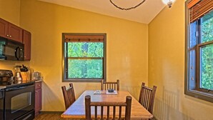 Une cuisine avec une table à manger, des chaises et une fenêtre donnant sur les arbres.