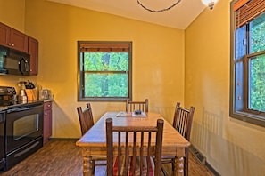 Una cocina con una mesa de comedor, sillas y un ventanal con vista a árboles.