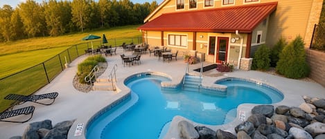 A swimming pool with a hot tub, surrounded by lounge chairs and a patio area.